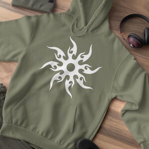 Puede incluir: Sudadera con capucha verde oliva con un dise&ntilde;o de sol blanco. La sudadera tiene un bolsillo delantero y una capucha con cord&oacute;n. Tambi&eacute;n se ven un gorro a juego, zapatillas negras y auriculares.