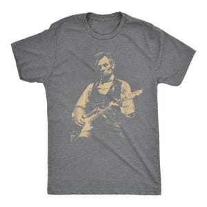 Peut inclure: T-shirt gris avec une image s&eacute;pia d'Abraham Lincoln jouant de la guitare &eacute;lectrique. Le graphisme montre Lincoln en gilet et chemise, tenant la guitare. Le t-shirt est fait d'une mati&egrave;re douce.