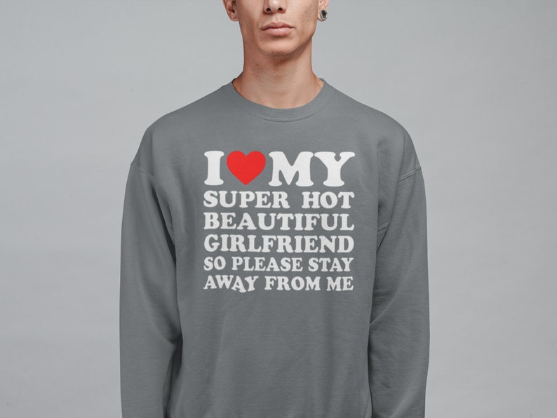 May include: Gray sweatshirt with white text that reads "I &hearts; MY SUPER HOT BEAUTIFUL GIRLFRIEND SO PLEASE STAY AWAY FROM ME". A red heart is in place of the word "love".