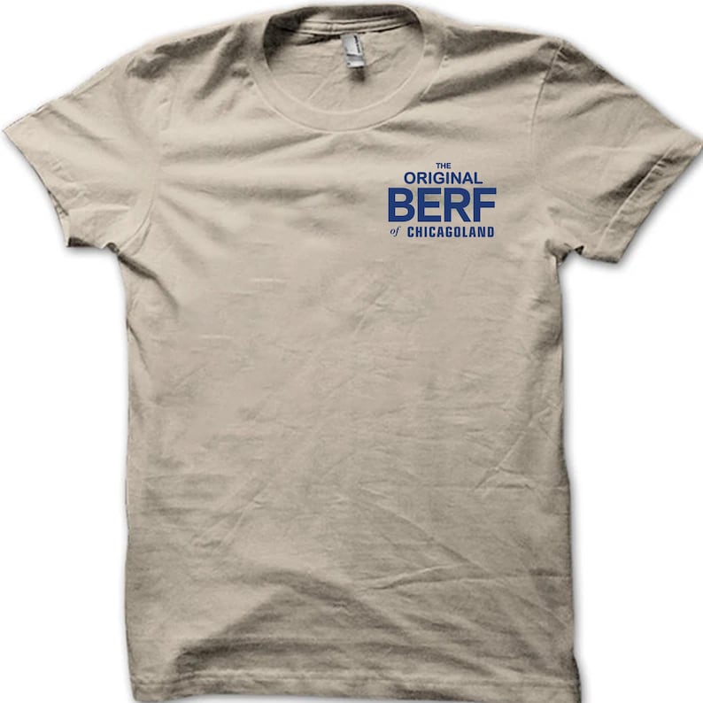 Pode incluir: Uma camiseta bege com um gr&aacute;fico azul que diz "The Original Berf of Chicagoland".