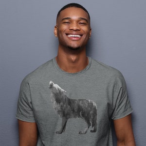 May include: A man wearing a heather grey t-shirt with a black and white wolf graphic. The wolf is howling at the moon.