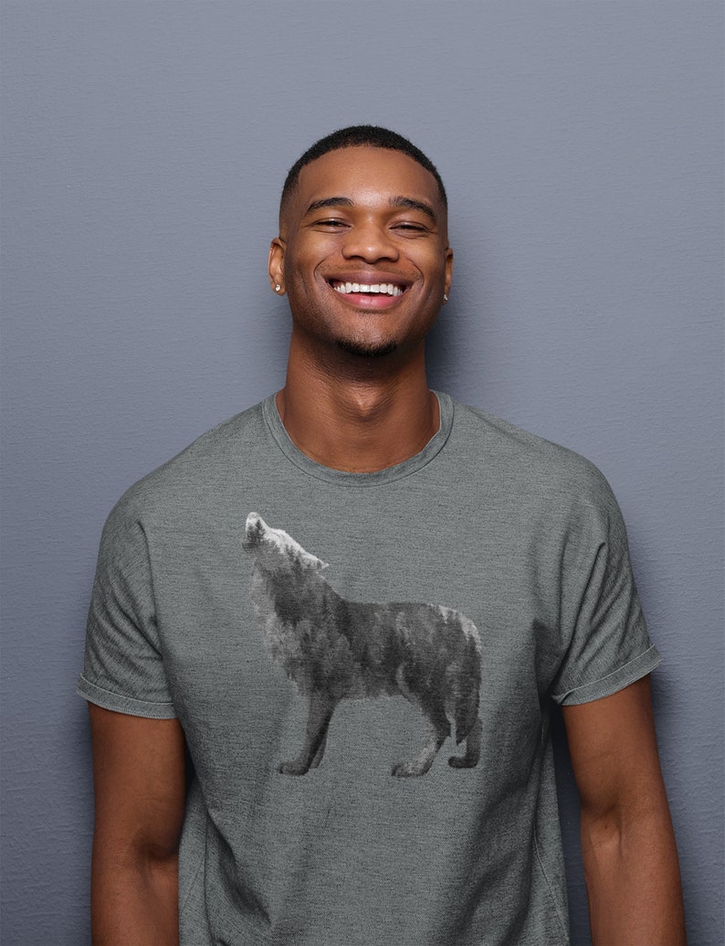 May include: A man wearing a heather grey t-shirt with a black and white wolf graphic. The wolf is howling at the moon.