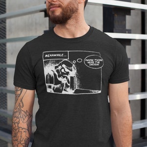 May include: Black t-shirt with a white graphic of a comic book panel. The panel shows a character with a thought bubble that says "Maybe those were the droids". The text "MEANWHILE..." is above the panel.