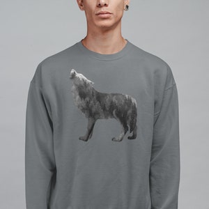 May include: A gray sweatshirt with a wolf silhouette design. The wolf is made up of a forest scene, with trees and foliage forming its shape.
