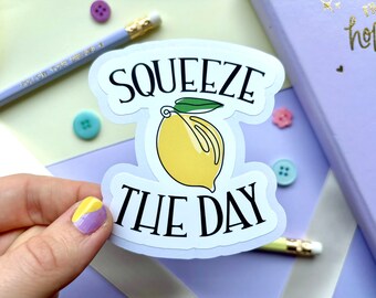 May include: White sticker with a yellow lemon and green leaves, and the text "Squeeze the Day" in black.