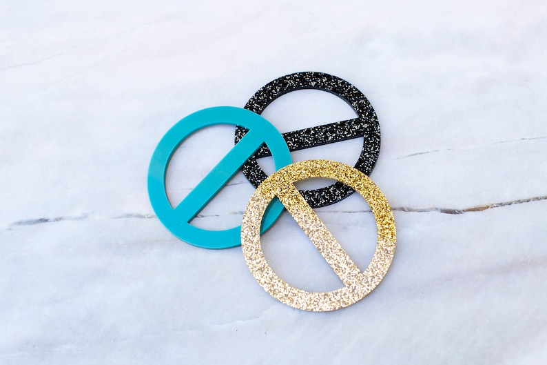 May include: Three decorative circle-shaped belt buckles. One is turquoise blue, one is black with glitter, and one is gold with glitter.