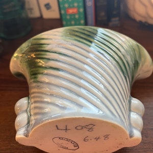 May include: A white ceramic vase with a green swirl design. The vase has a rounded bottom and a wide opening. The bottom of the vase is marked with "McMaster Canada" and the numbers "4 08 6 4 8".