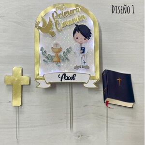 Può includere: Un set di topper per torta per una prima comunione. Il topper presenta un bambino con un abito bianco che tiene una bibbia, un calice, una colomba e le parole "Mi Primera Comunión". Il set include anche una croce dorata e un piccolo libro blu con una croce sulla copertina. Il topper è su un bastoncino di acrilico trasparente.