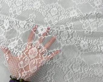 May include: White lace fabric with a delicate floral pattern. The lace is sheer and has a soft, flowing texture.