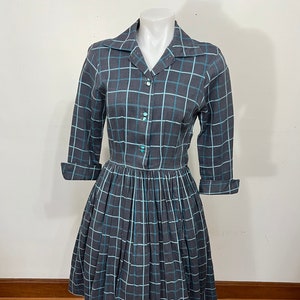 May include: A gray and white plaid dress with a collared neckline and 3/4 sleeves. The dress has a fitted bodice and a full skirt.