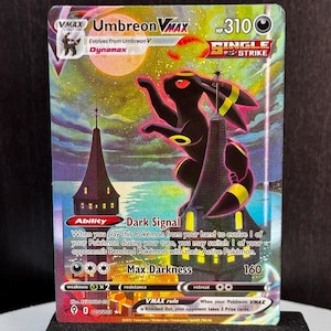 May include: Umbreon VMAX Pokémon card featuring a black and yellow creature with a cityscape background. The card displays the text "Dark Signal" and "Max Darkness". The card is displayed on a black stand.