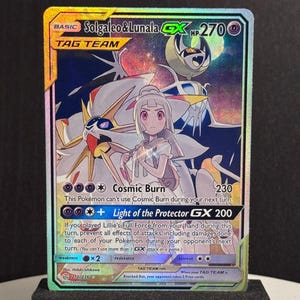 Può includere: Carta Pokémon olografica Solgaleo & Lunala GX Tag Team. La carta presenta un'illustrazione dettagliata dei due Pokémon e un allenatore. La carta ha 270 HP e include i testi "Cosmic Burn" e "Light of the Protector GX 200".