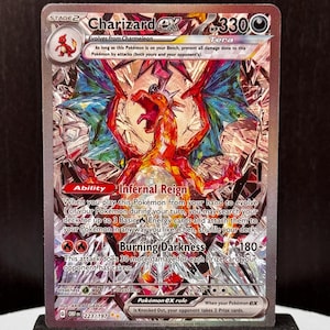 May include: A Charizard ex Pokémon card. The card features a vibrant illustration of a fiery dragon with red, orange, and blue hues. The card has the text "Charizard ex" and "Burning Darkness" with a damage value of 180+.