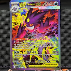Może przedstawiać: Holograficzna karta kolekcjonerska Pokémon Mega Gengar EX. Karta przedstawia fioletowego Gengara z groźnym uśmiechem na tle żywego, kolorowego tła. Tekst zawiera "Mega Gengar EX", "Shadowy Concealment" i "Void Gale".