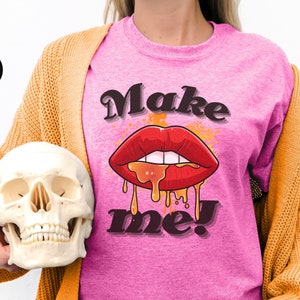 Può includere: Maglietta rosa con una grafica di una bocca rossa, che cola, ricoperta di miele e il testo "Make me!"