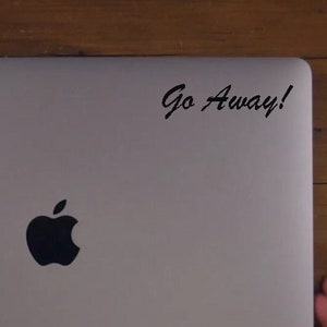 May include: A silver laptop computer with a black Apple logo and a sticker that says "Go Away!" on the top right corner.