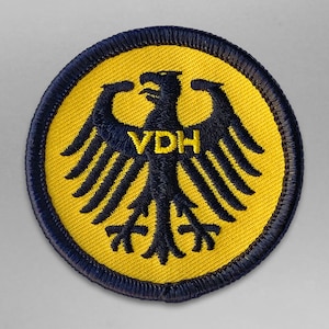 以下が含まれることがあります： ドイツの鷲とVDHの文字が刺繍された黄色と黒のワッペンです。
