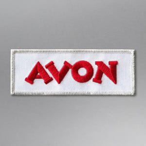 May include: White embroidered patch with the word "AVON" in red lettering.
