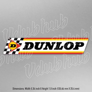 Könnte beinhalten: Ein weißer, roter und gelber Aufkleber mit dem Wort "DUNLOP" in schwarzen Buchstaben. Der Aufkleber zeigt außerdem eine karierte Flagge mit einem roten "D" in der Mitte. Der Aufkleber ist 13,56 cm breit und 2,54 cm hoch.
