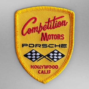 Puede incluir: Parche bordado amarillo con el texto "Competition Motors Porsche Hollywood Calif" y dos banderas a cuadros blancas y negras.