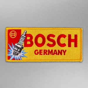 Puede incluir: Parche bordado amarillo y rojo con el logotipo de Bosch y el texto "BOSCH GERMANY". El logotipo presenta una bujía estilizada.