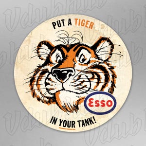 May include: Circular vintage sign with a tiger's head in orange and black. The sign displays the text "PUT A TIGER IN YOUR TANK!" and the Esso logo within a blue oval.