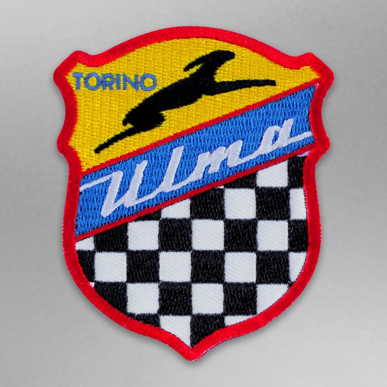 May include: A red, yellow, and blue embroidered patch with a black silhouette of a rabbit jumping over a checkered flag. The patch says "Torino Ulma" in white text.