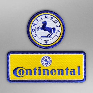 Op de afbeelding: Twee blauwe en gele geborduurde patches met het Continental Tire-logo. De grotere patch toont een wit paard met een blauwe manen en staart. De kleinere patch toont het Continental Tire-logo in blauw en geel.