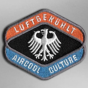 Peut inclure: Écusson brodé avec un fond noir, des bordures orange et bleu, et les mots "LUFTGEKÜHLT" et "AIRCOOL CULTURE". Un emblème d'aigle blanc est centré sur l'écusson. L'écusson a une bordure grise.