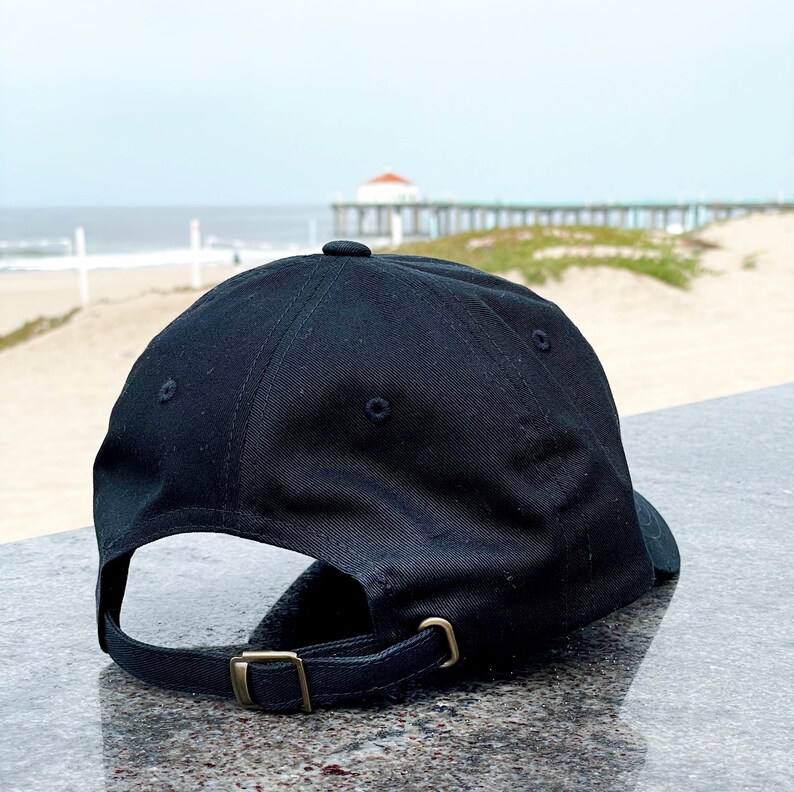May include: A black baseball cap with a brown adjustable strap. The cap is made of a soft, cotton fabric.