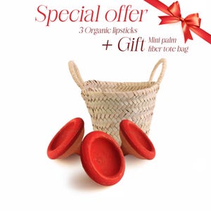 Puede incluir: Tres envases de lápiz labial rojos y una cesta tejida con el texto "Oferta especial 3 lápices labiales orgánicos + Regalo Mini bolso de fibra de palma"