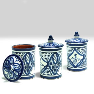 Op de afbeelding: Drie blauwe en witte keramische potten met deksels. De potten hebben een traditioneel Marokkaans ontwerp met ingewikkelde patronen en blauwe accenten. De deksels hebben een knop bovenop.