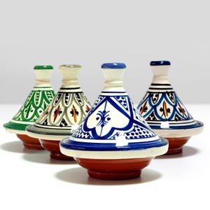 May include: Four ceramic tagines with different colored and patterned glazes. The tagines are white with blue, green, and gray designs.