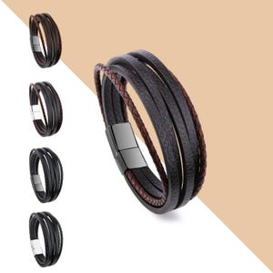 May include: A multi-layered leather bracelet with a magnetic clasp. The bracelet is made of brown and black leather and has a braided design.