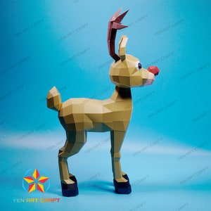 May include: A papercraft reindeer model with a red nose and brown antlers. The reindeer is standing on a blue background.