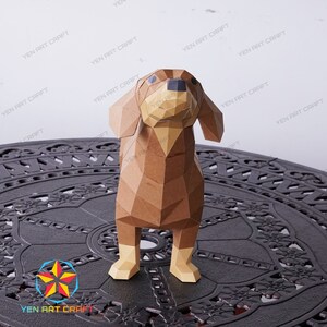 May include: A brown papercraft dachshund dog model standing on a black metal table with a decorative design. The dog is looking up with its head tilted.