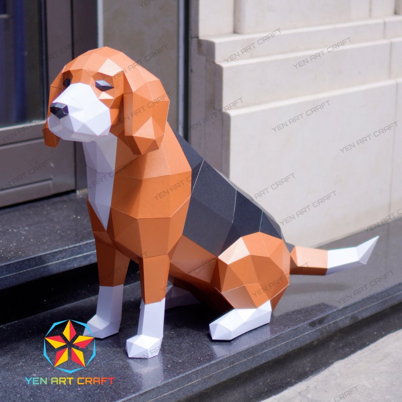 Puede incluir: Un modelo de papel de un perro beagle sentado en un conjunto de escaleras. El perro est&aacute; hecho de papel marr&oacute;n, negro y blanco y tiene un aspecto realista. El perro est&aacute; sentado en un conjunto de escaleras grises con una pared blanca en el fondo.