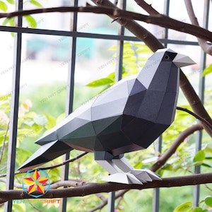 May include: A black and gray papercraft crow perched on a branch. The crow is made of folded paper and has a detailed design.