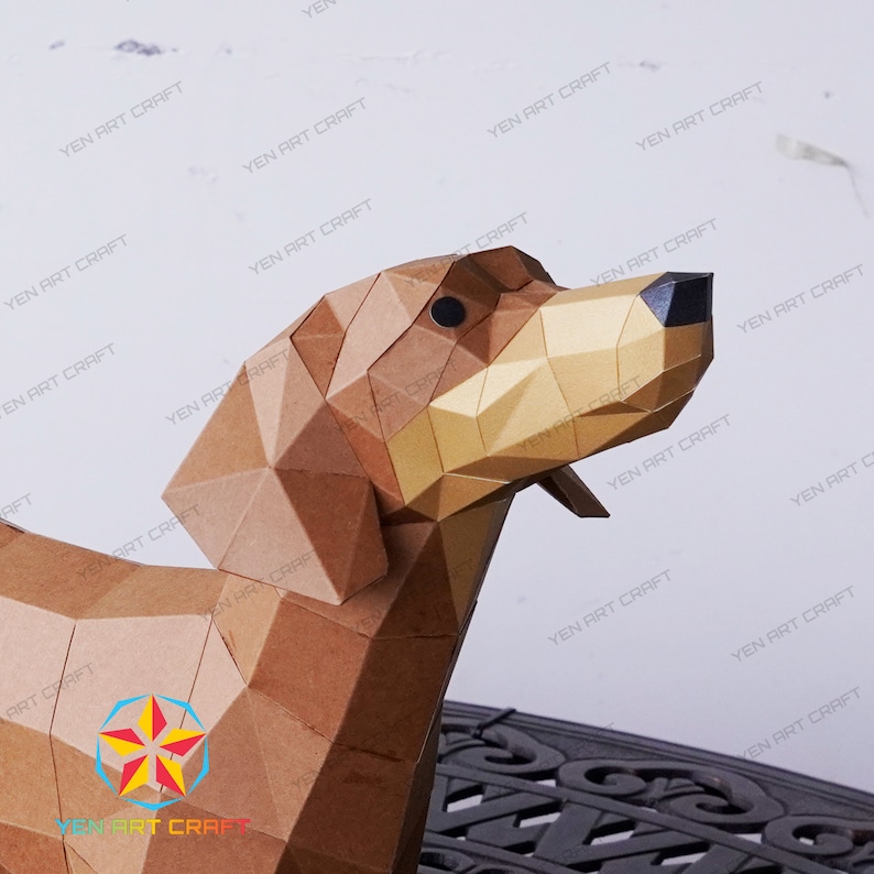 May include: A brown papercraft model of a dog's head, with a gold-colored ear and black eyes. The model is made up of many small triangles and is a 3D representation of a dog.