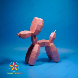 May include: A pink paper balloon dog sculpture against a blue background. The sculpture is made of geometric shapes and has a tail, legs, and a head. The text "YEN ART CRAFT" is visible in the image.