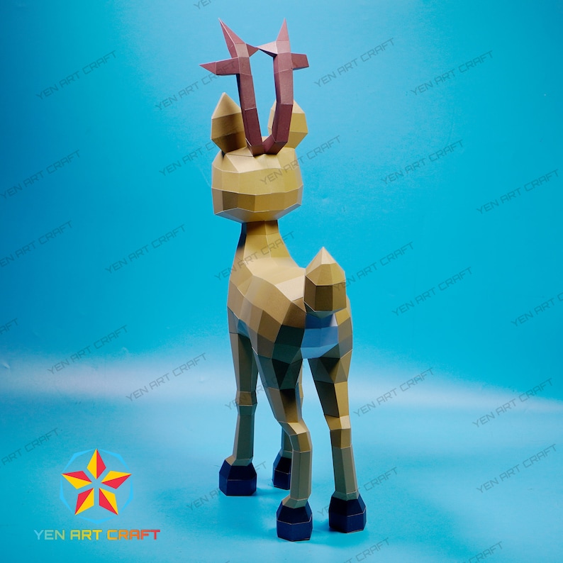 May include: A papercraft model of a deer with brown antlers and a light brown body. The deer is standing on a blue surface.