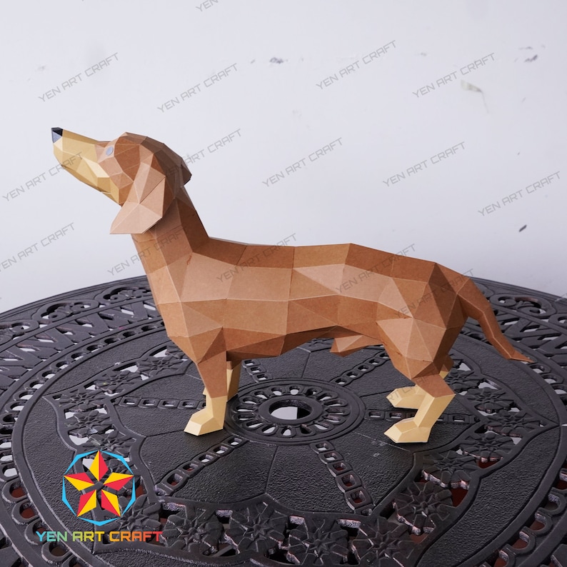 May include: A brown papercraft dachshund model, standing on a black circular table with an intricate design. The model is made of folded paper and has a realistic appearance.