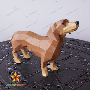 May include: A brown papercraft model of a dachshund dog standing on a black metal surface with a decorative pattern. The dog is made of many small triangles that create a geometric design.