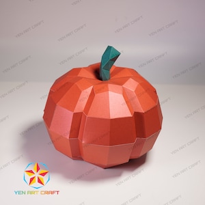 May include: A 3D papercraft pumpkin with a green stem. The pumpkin is made of orange paper and has a geometric design.
