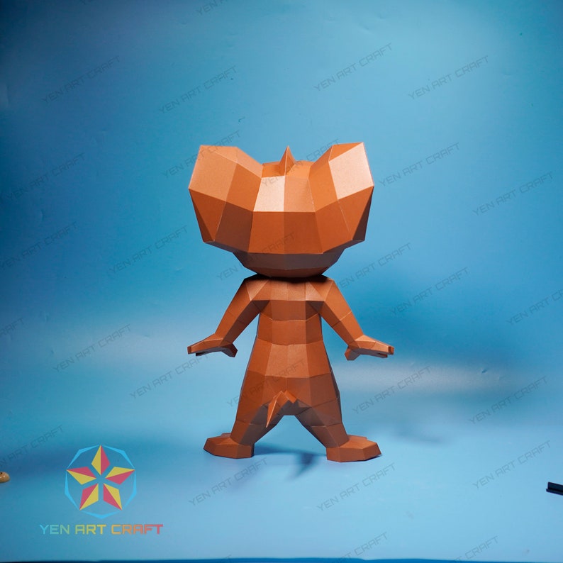 May include: A brown papercraft model of a cartoon character, resembling a mouse, standing with its back to the viewer. The model is made of folded paper and has a detailed design.