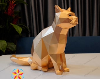 May include: A gold papercraft model of a cat sitting with its tail curled around its legs. The model is made of many small triangles that create a geometric pattern.