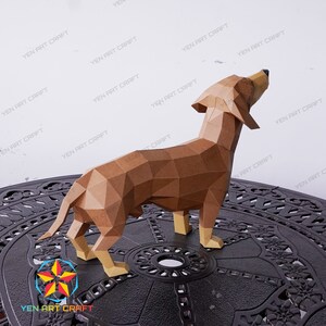 May include: A brown papercraft model of a dachshund dog standing on a black metal table. The dog is looking up and has a long snout and short legs.