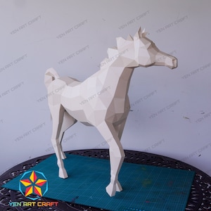 May include: A white papercraft horse model, standing on a green cutting mat. The horse is made of folded paper and has a realistic appearance.