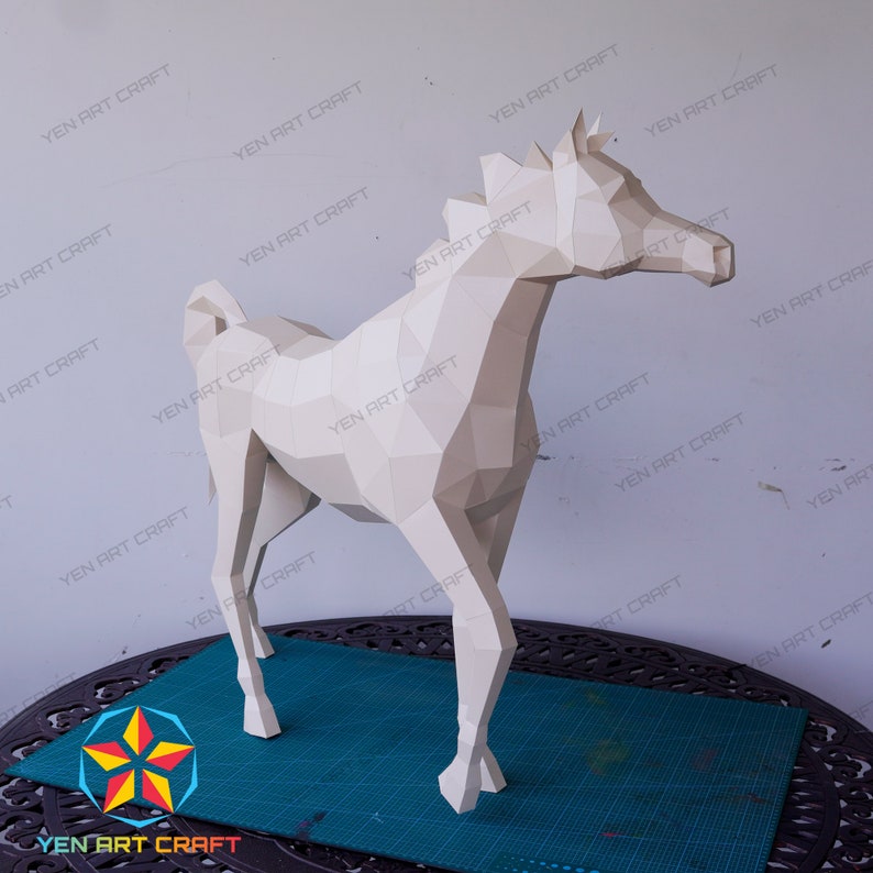 May include: A white papercraft horse model, standing on a green cutting mat. The horse is made of folded paper and has a realistic appearance.