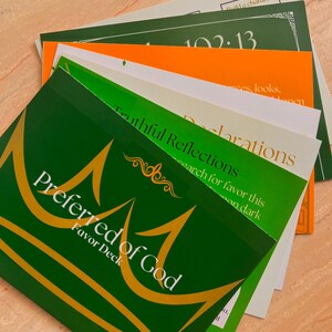 May include: A stack of colorful cards with text and gold accents. The top card is green with the words "Preferred of God" and a gold crown design. Other cards are orange, white, and green, with phrases like "Truthful Reflections" and "Declarations".